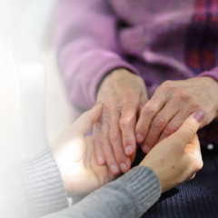 A caregiver holding the hands of a senior with dementia.