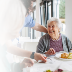 Senior enjoying a meal with caregiver support during a respite care stay